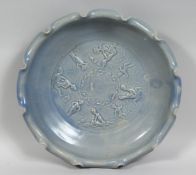 A LARGE CHINESE BLUE GLAZED POTTERY BOWL with petal-form rim, the centre with relief decoration of