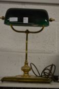 A brass desk lamp with green glass shade.