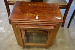 A next of four brass inlaid hardwood tables.