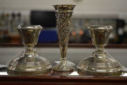 A pair of dwarf silver candlesticks and an embossed silver bud vase.