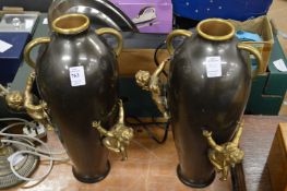 A pair of decorative bronze metal vases, mounted with cherubs.