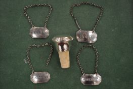 Four silver decanter labels and a silver bottle stopper.