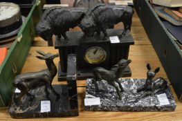 A small mantle clock mounted with bison together with a bookend and another item.
