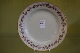 A circular plate decorated with grape and vine border.