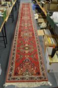 A Persian style red ground floral decorated long runner 700cms x 78cms.