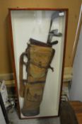 An old golf bag and clubs mounted in a display case.