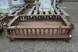 An Indian hardwood rectangular cradle or plant trough with turned spindle supports.