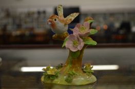 A Crown Staffordshire model of a bird on a branch by J T Jones.