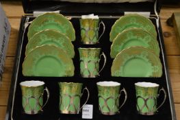 A cased set of six Coalport coffee cups and saucers, green ground with gilt decoration, the cups