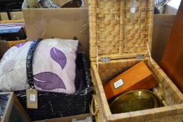 Two wicker baskets containing decorative cushions, a brass oval dish a wooden champagne box and a