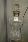 An hourglass decanter with silver collar.