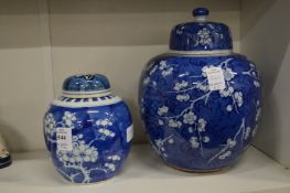 A Chinese prunus pattern ginger jar and cover and a similar larger jar and cover.