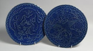 A PAIR OF CHINESE BLUE GLAZED CIRCULAR PLAQUES, one carved with a dragon, the other with an exotic