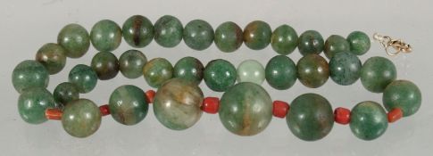 A SET OF GRADUATED JADE BEADS, the larger beads with small coral beads between.