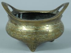 A SMALL CHINESE BRASS TWIN HANDLE TRIPOD CENSER, 13.5cm wide (handle to handle).