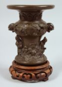A SMALL JAPANESE BRONZE VASE with hardwood stand, the vase relief cast with figures and twin lion