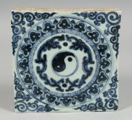 A CHINESE BLUE AND WHITE TEMPLE TILE with decorative motif depicting a yin-yang symbol. 19.5cm