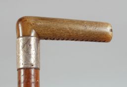 AN ANTIQUE RHINO HORN HANDLE WALKING STICK, with silver band, 86cm long.**Pleas