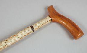 AN ANTIQUE SHARK VERTEBRAE WALKING STICK, with wooden handle, 90cm long.