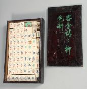 A CHINESE BOXED MAH JONG SET with bone and wood counters, box 26.5cm x 16cm.
