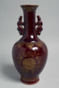 A CHINESE OX BLOOD GLAZE TWIN HANDLE VASE, the body with gilt decoration depicting the longevity