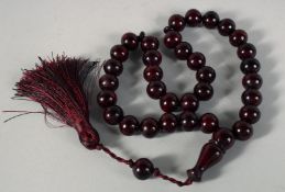 A SET OF DARK RED CHERRY AMBER BAKELITE TESBIH PRAYER BEADS, each bead approx. 13mm diameter.