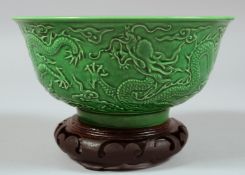 A CHINESE GREEN GLAZED PORCELAIN DRAGON BOWL with hardwood stand, the exterior with carved