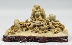 A GOOD CHINESE SOAPSTONE CARVING of a landscape scene with buildings amongst mountains, mounted to a