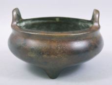 A CHINESE BRONZE TWIN HANDLE TRIPOD CENSER, with four character mark to base, 15cm diameter.