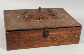 A LARGE INDIAN CARVED WOOD LIDDED BOX carved all over with various figures and beasts, the hinged