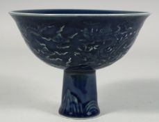 A CHINESE SACRIFICIAL BLUE GLAZE PORCELAIN STEM CUP, the exterior with raised decoration depicting