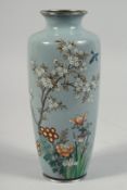 A JAPANESE BLUE GROUND CLOISONNE VASE, decorated with a spray of native flora, 21.5cm high.