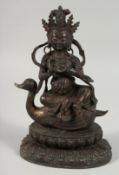 A LARGE BRONZE FIGURE OF A SEATED DEITY, sat upon a bird and on a lotus base, with traces of gilt,