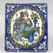 A PERSIAN GLAZED POTTERY TILE, central depicting a seated figure within a floral border, 24cm x 21.