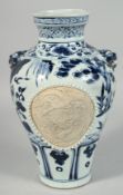 A CHINESE BLUE AND WHITE TWIN HANDLE PORCELAIN VASE, the body with two unglazed panels of a carved
