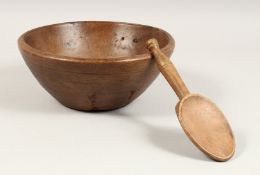 A TREEN CIRCULAR BUTTER BOWL AND SPOON. 10.5ins diameter.