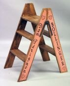 A PAIR OF CHAMPAGNE ADVERTISING FOLDING STEPS.