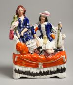 A STAFFORDSHIRE FLAT BACK GROUP, two figures on a sofa. 12ins high.
