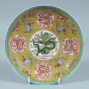 A CHINESE FAMILLE JAUNE CIRCULAR DISH decorated with dragons. 8ins diameter.