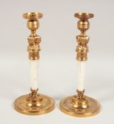 A PAIR OF ROCK CRYSTAL AND GILT METAL EGYPTIAN DESIGN CANDLESTICKS on circular bases. 11.5ins high.