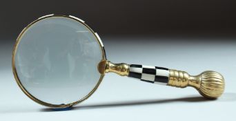 A MAGNIFYING GLASS with checkered and gilt handle.