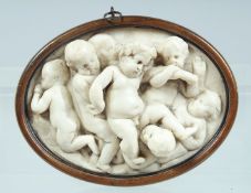 A CARVED MARBLE OVAL FRAMED PLAQUE OF CUPIDS. 6ins x 4ins