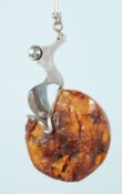 AN AMBER AND SILVER DESIGNER PENDANT.