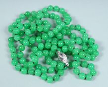 A STRING OF JADE BEADS, long row with white gold clasp.