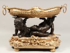 A SUPERB BRONZE AND GILT BRONZE OVAL TWO HANDLED CHERUB BOWL held by two cupids. 15ins high, 21ins