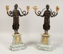 A PAIR OF EMPIRE DESIGN BRONZE AND GILT METAL, TWO BRANCH CANDELABRA held aloft by bronze