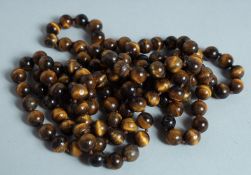 A STRING OF TIGER'S EYE BEADS.