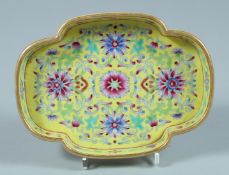 A CHINESE SHAPED FAMILLE JAUNE DISH. 5.75ins diameter.