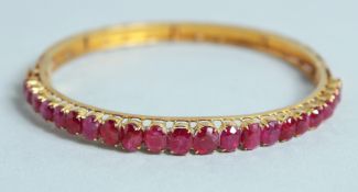 A GOOD 18CT GOLD RUBY SET BANGLE.