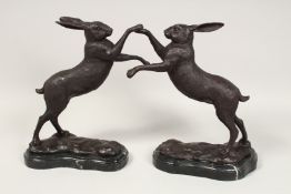 A PAIR OF BRONZE BOXING HARES on a marble base. 12ins high.